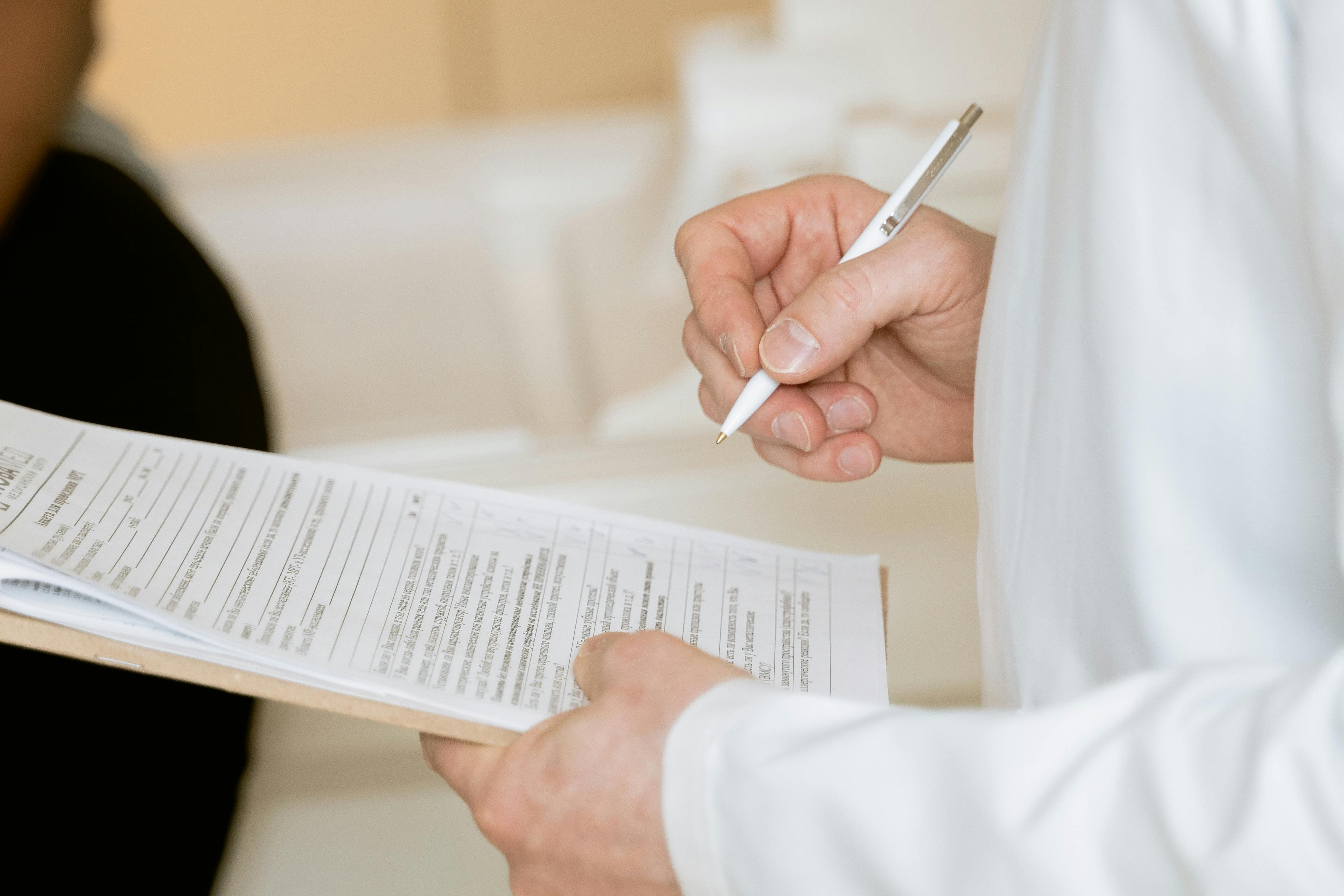 Photo Of Person Holding Paper And Pen